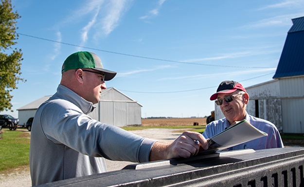 Farmer talks with Farm Credit crop insurance agent at truck tailgate